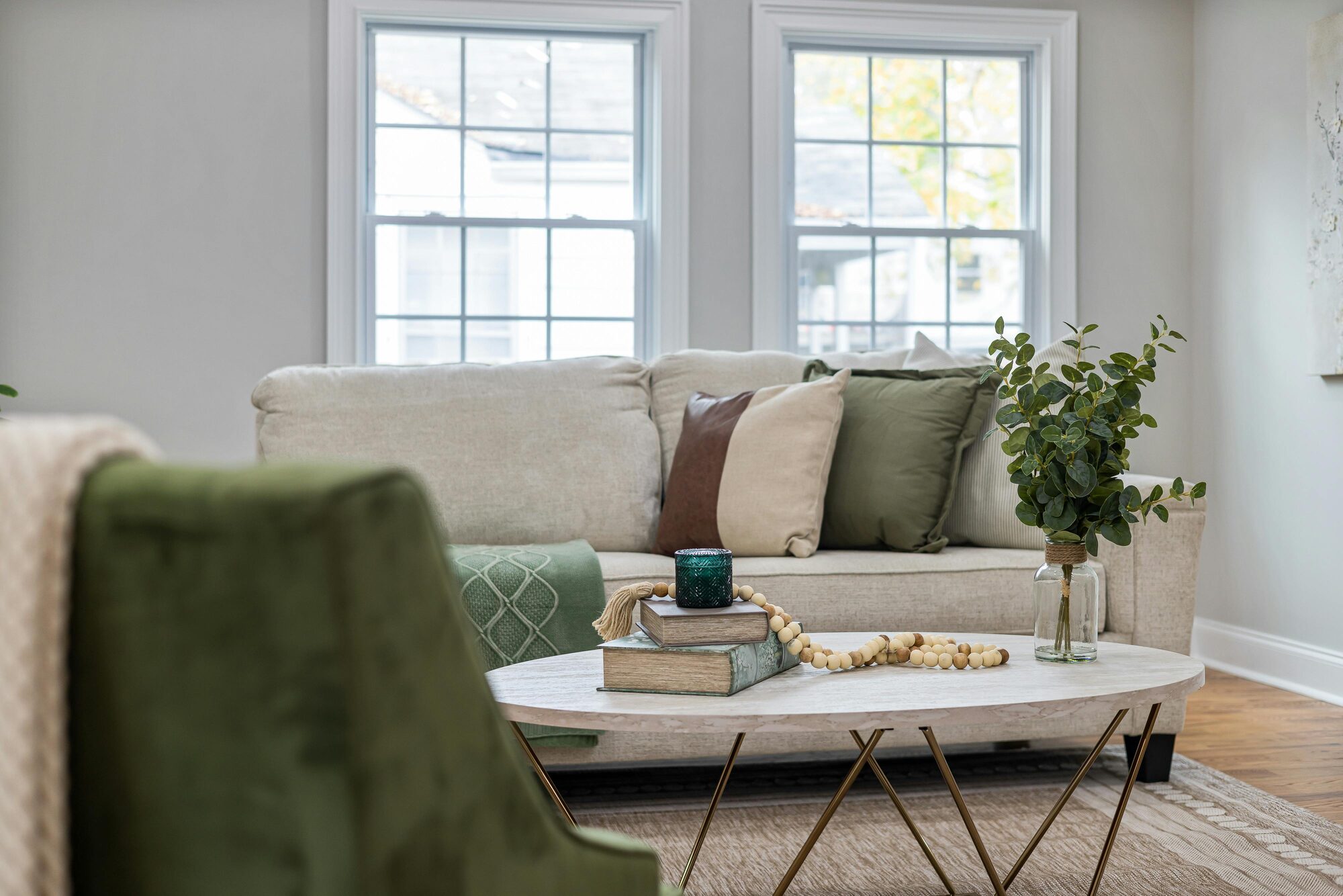 Modern living area with green accents and neutral sofa by Kaizen Homes in Fairview, NC