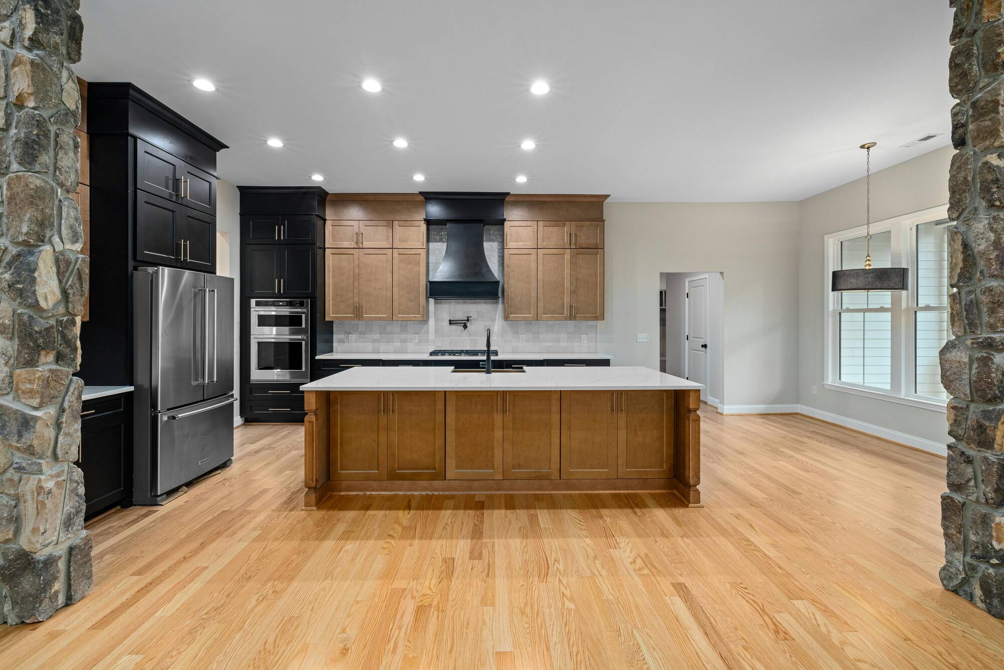 Open-concept kitchen with wood and black cabinetry by Kaizen Homes in Swannanoa, NC
