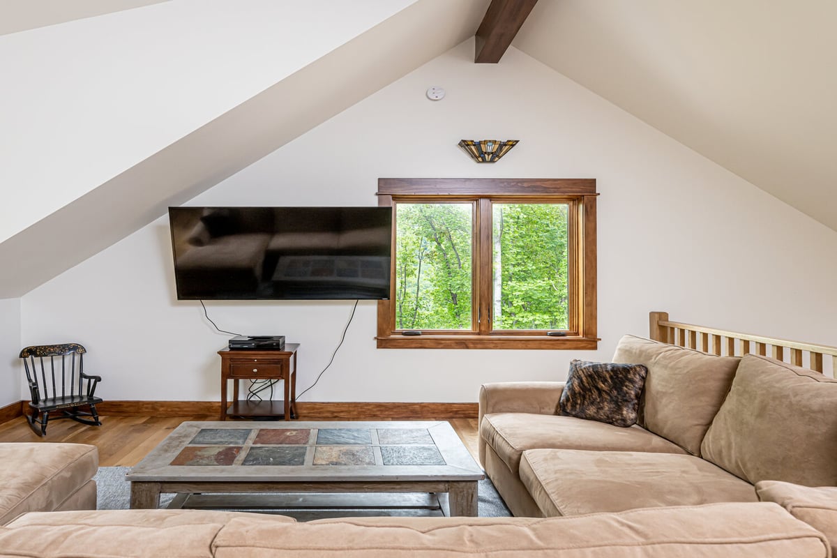 Bonus loft space with neutral furnishings and forest views by Kaizen Homes