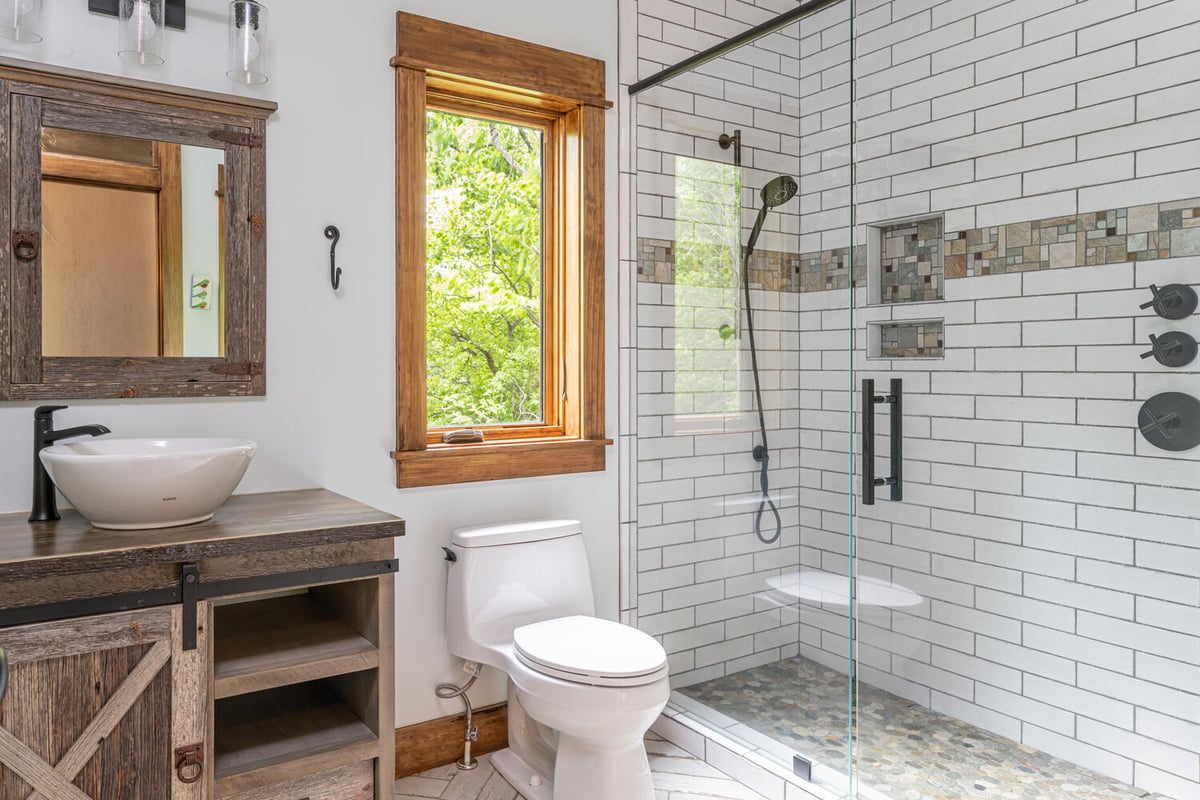 Custom home bath with modern fixtures and reclaimed wood vanity by Kaizen Homes