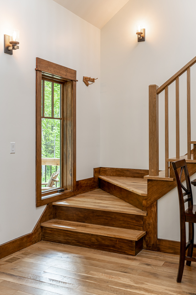 Wood staircase with large window in a custom mountain home by Kaizen Homes