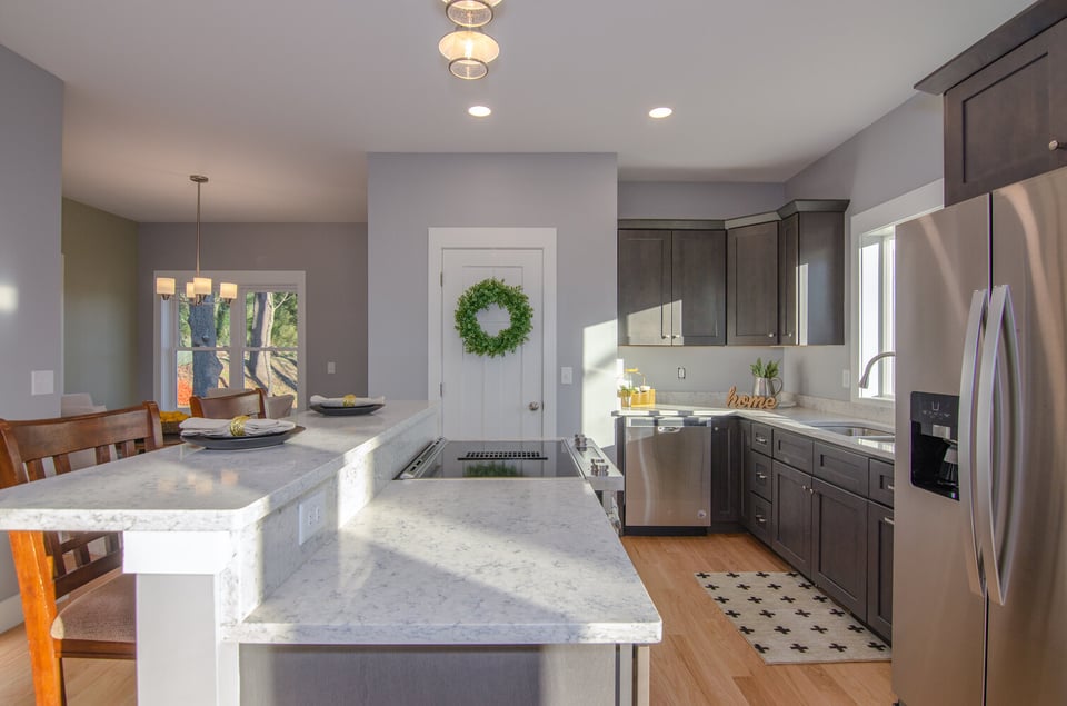 Modern kitchen with white quartz countertops and dark cabinets by Kaizen Homes in Ca