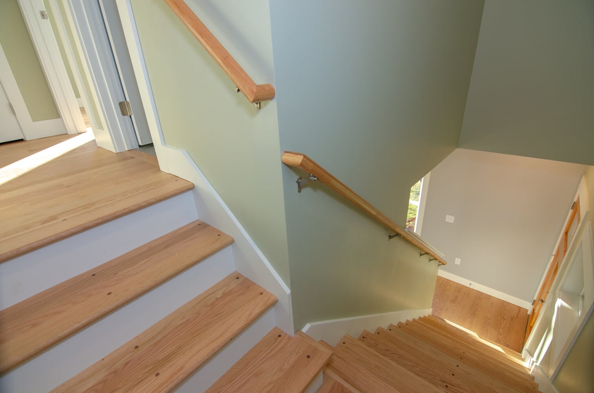 Modern wood staircase with green accent wall in a Kaizen Homes home in Canton, NC