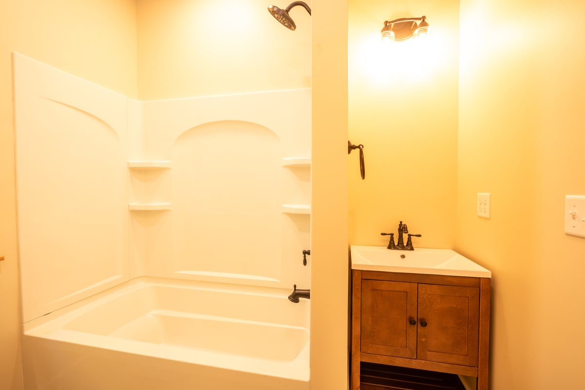 Cozy bathroom with soft yellow lighting and classic tub design in a Kaizen Homes p