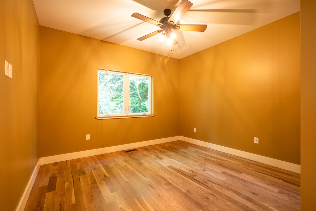 Custom-built bedroom with ceiling fan and natural light by Kaizen Homes