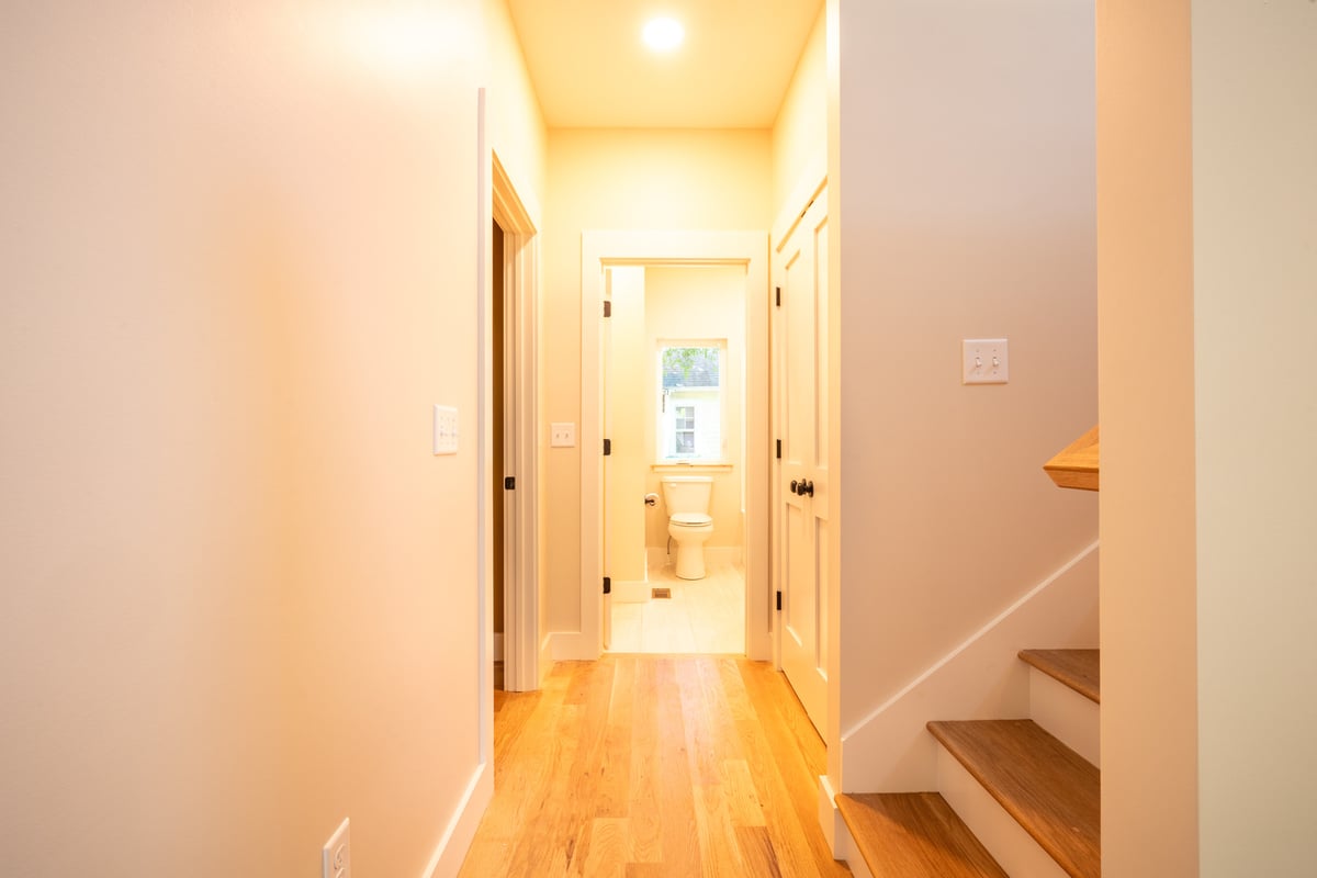 Light-filled bathroom with clean white fixtures and warm wood accents by Kaizen Ho