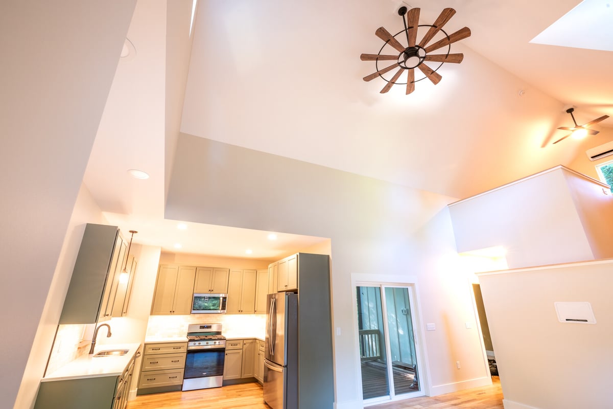 Open-concept design with dual ceiling fans and modern kitchen by Kaizen Homes