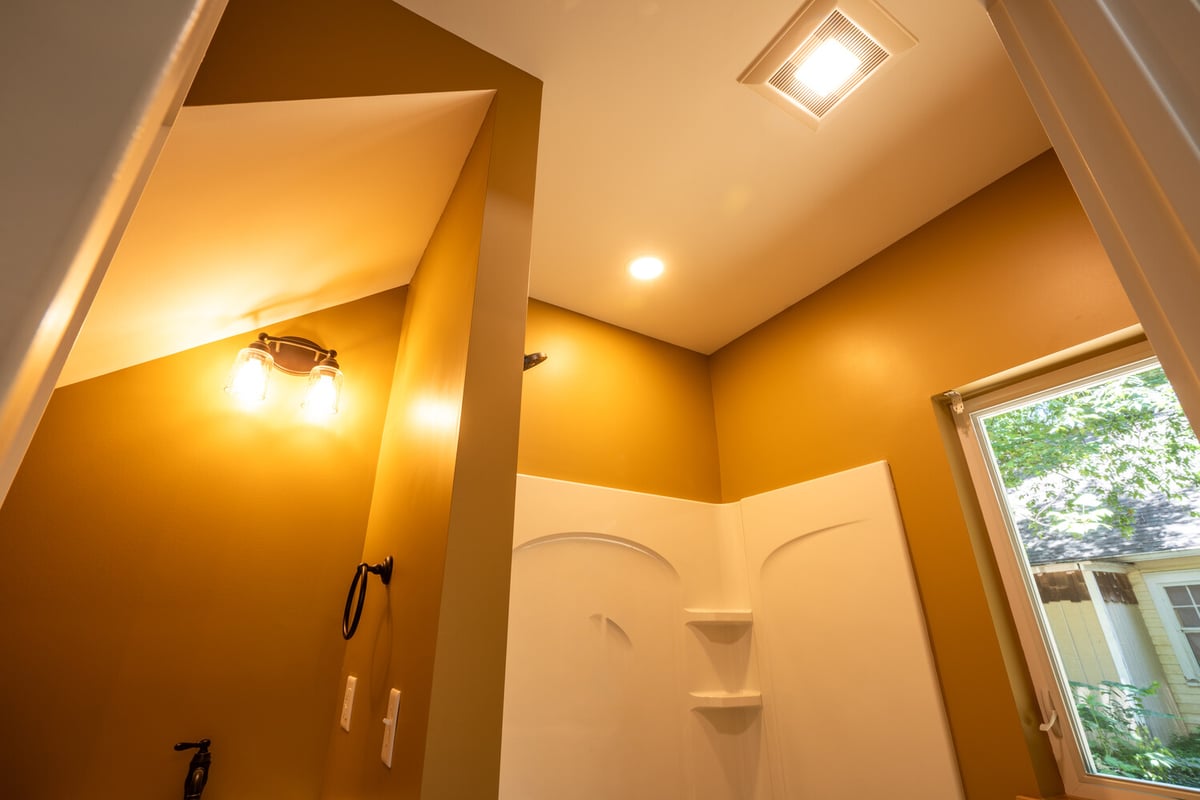 Recessed lighting and bright shower walls in new bathroom build by Kaizen Homes