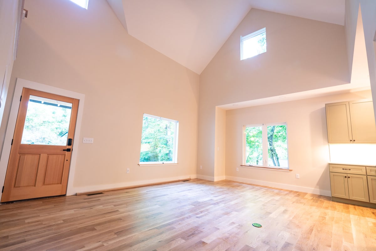 Spacious great room with wide windows and light wood flooring in a Kaizen Homes