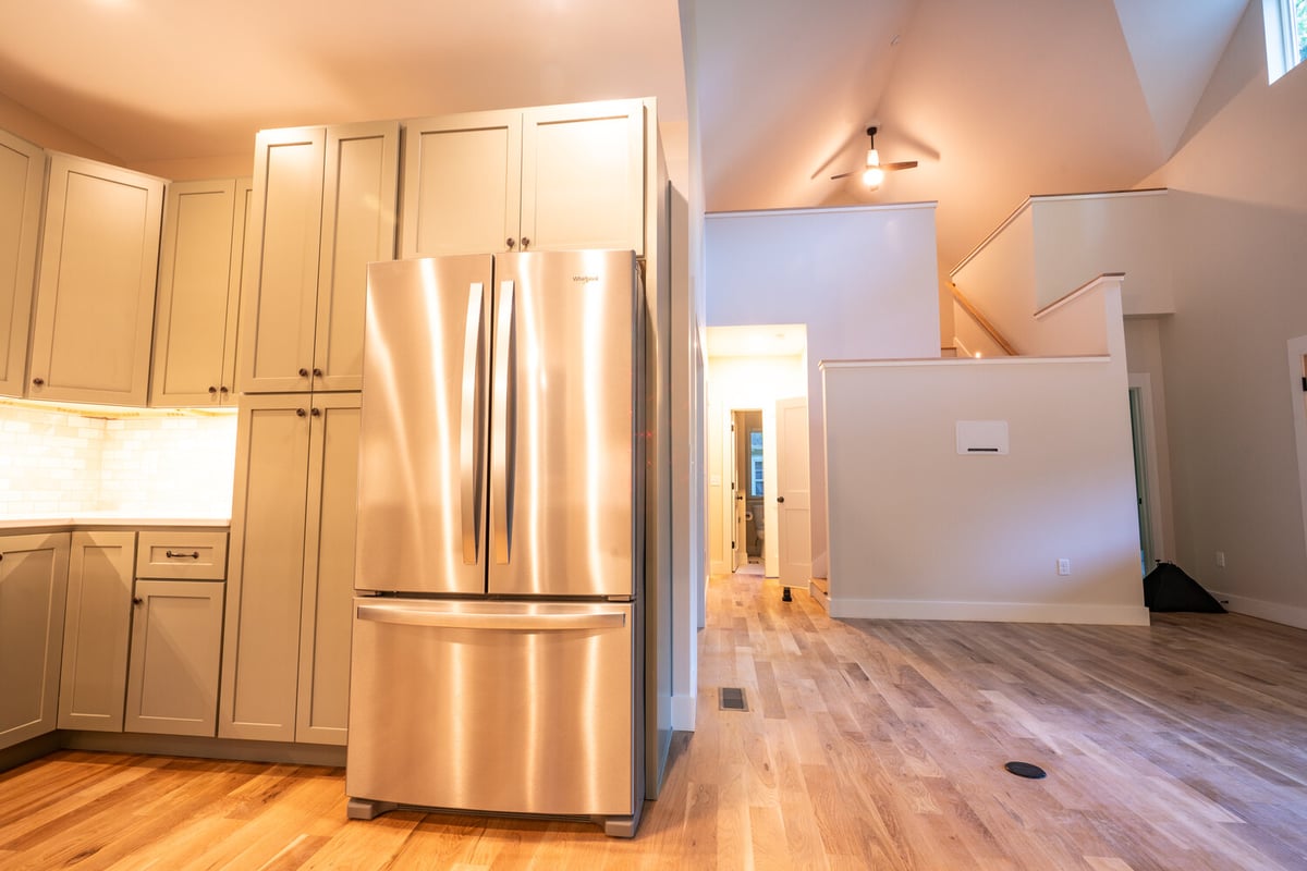 Stainless refrigerator and built-in cabinetry in kitchen of Kaizen Homes