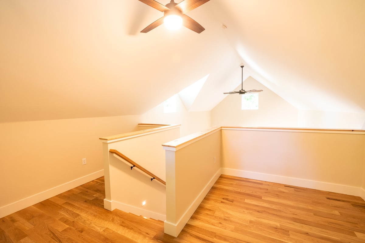 Upper loft area with natural light and vaulted ceiling in a custom home by Kaizen