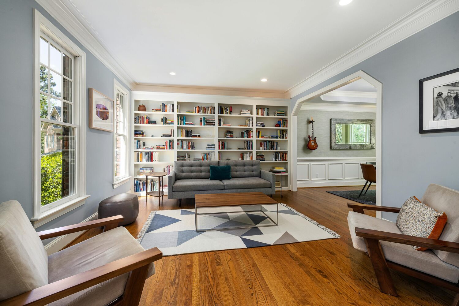 Stylish sitting room with hardwood floors and open bookshelf wall by Kaizen Homes in Marshall, NC