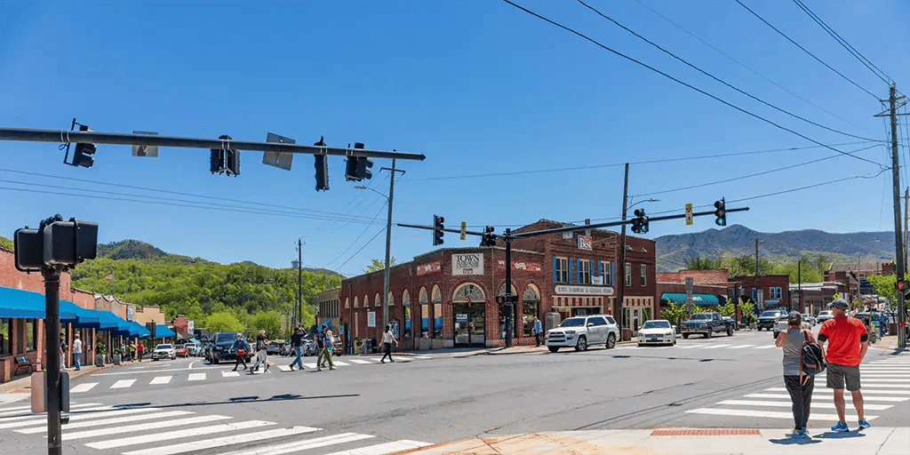 A photo of an intersection in downtown Black Mountain with cars, pedestrians, street lights, and businesses lining the streets.